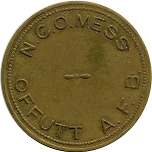 May include: A round, bronze-colored token with the text "N.C.O. MESS B.A.F. OFFUTT" around the edge. A small propeller-like design is in the center. The token has a beaded border.
