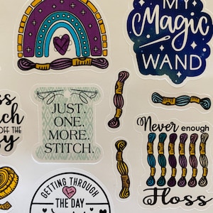 May include: A set of colorful stickers featuring embroidery and needlework themes. The stickers include a rainbow with a heart, a needle and thread, a spool of thread, and the text "My Magic Wand". Other stickers include the text "Just One More Stitch", "Getting Through The Day One Stitch At A Time", "Never Enough Floss", and "Make Time".