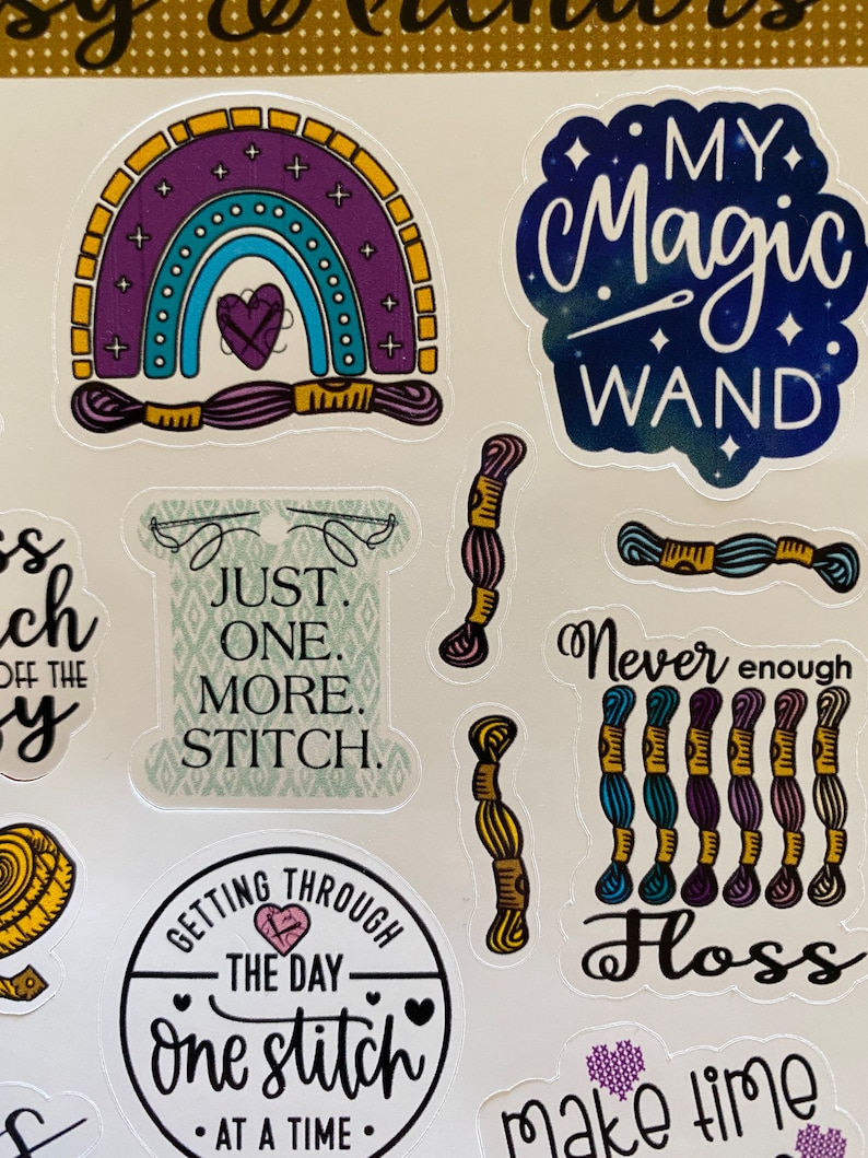 May include: A set of colorful stickers featuring embroidery and needlework themes. The stickers include a rainbow with a heart, a needle and thread, a spool of thread, and the text "My Magic Wand". Other stickers include the text "Just One More Stitch", "Getting Through The Day One Stitch At A Time", "Never Enough Floss", and "Make Time".