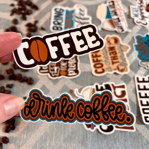 以下が含まれることがあります： コーヒーをテーマにしたステッカーのセット。様々なデザインがあり、「COFFEE」にはコーヒー豆、「drink coffee」はカラフルな手書き風、「COFFEE is cheaper than therapy」などがあります。