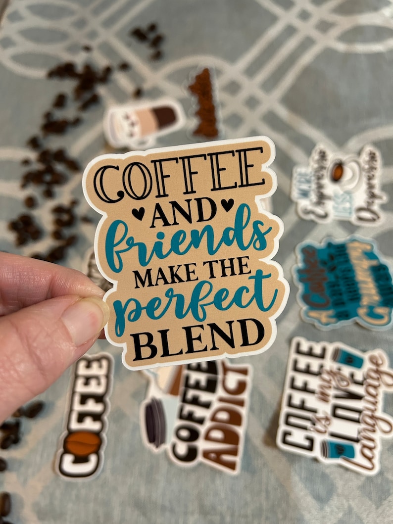 以下が含まれることがあります： 黒とターコイズブルーの文字で「COFFEE AND friends MAKE THE perfect BLEND」と書かれた、茶色とベージュのステッカー。ステッカーは「AND」の周りにハートの形をしています。