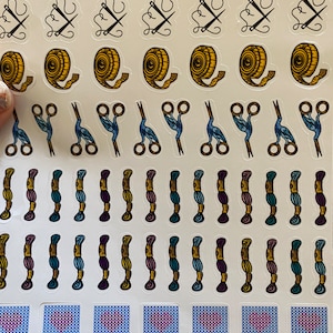 May include: A sheet of colorful stickers featuring sewing and crafting themed designs. The stickers include images of scissors, tape measures, thread spools, needles, and hearts.