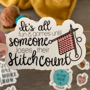 May include: A white sticker with the text "It's all fun & games until someone loses their stitch count." The sticker features a pink knitted square and knitting needles. Other stickers with yarn-related themes are visible.
