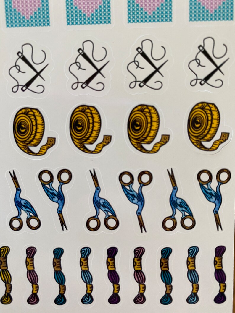 May include: A sheet of stickers featuring various sewing and crafting supplies, including needles, thread, scissors, and measuring tape. The stickers are colorful and feature a variety of designs.