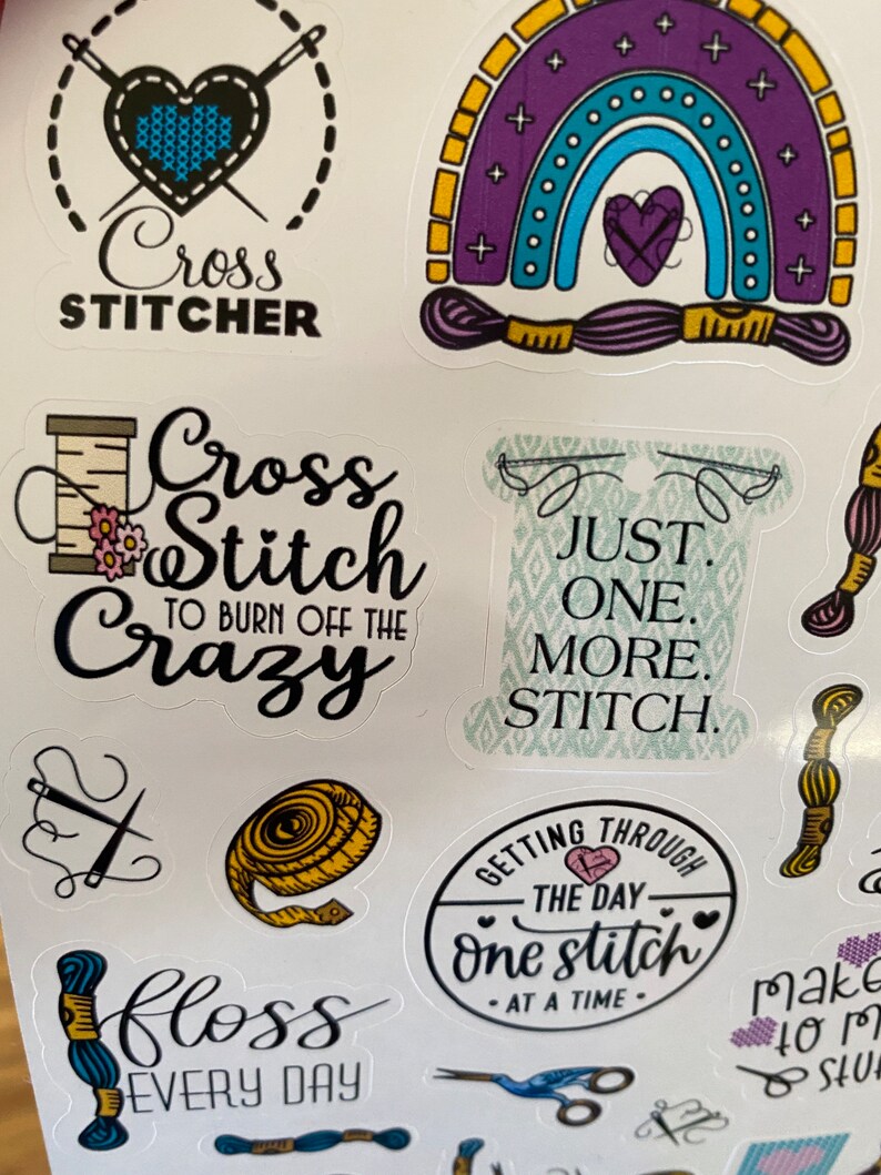 May include: A set of colorful cross stitch themed stickers with various designs and sayings, including "Cross Stitch to Burn Off the Crazy", "Just One More Stitch", "Getting Through the Day One Stitch at a Time", and "Floss Every Day".
