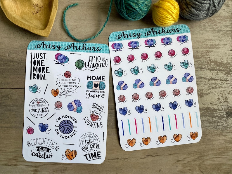 Peut inclure: Deux feuilles d'autocollants avec une vari&eacute;t&eacute; d'illustrations color&eacute;es sur le th&egrave;me du crochet. Les autocollants comprennent des pelotes de laine, des crochets &agrave; crochet et des phrases comme "Juste une rang&eacute;e de plus" et "La maison est l&agrave; o&ugrave; est la laine".