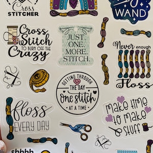 May include: A set of 14 colorful stickers featuring cross-stitch themed designs. The stickers include phrases like "Cross Stitcher", "Just One More Stitch", "Getting Through The Day One Stitch At A Time", "Make Time To Make Stuff", and "Shhh... I'm Counting Stitches!"