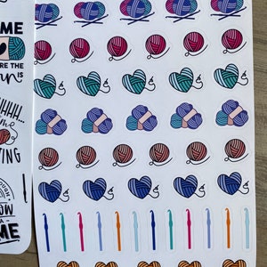 Peut inclure: Une feuille d'autocollants color&eacute;s repr&eacute;sentant diff&eacute;rents pelotes de laine, des c&oelig;urs et des crochets. Les autocollants sont dispos&eacute;s en rang&eacute;es et en colonnes sur un fond blanc. Le texte "Artsy Arthurs" est imprim&eacute; en haut de la feuille.