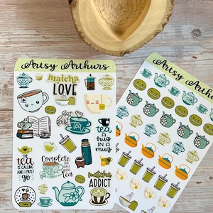 May include: Two sticker sheets with tea-themed designs. One sheet features various tea-related illustrations, including teacups, teapots, and text like "Matcha Love" and "Tea Addict." The other sheet has repeating patterns of teapots, macarons, and tea cups.