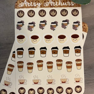 Pu&ograve; includere: Due fogli di adesivi con varie illustrazioni a tema caff&egrave;. Gli adesivi includono tazze da caff&egrave;, chicchi di caff&egrave; e tazze fumanti. Il testo "Artsy Arthurs" &egrave; stampato nella parte superiore dei fogli.