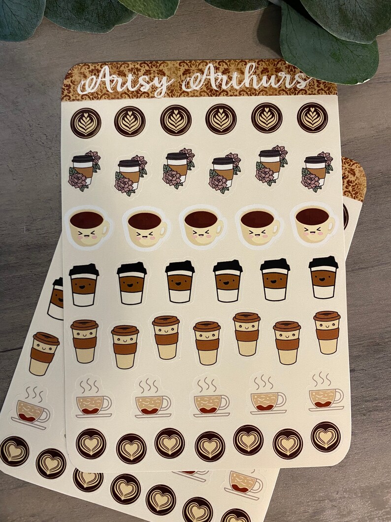 Pu&ograve; includere: Due fogli di adesivi con varie illustrazioni a tema caff&egrave;. Gli adesivi includono tazze da caff&egrave;, chicchi di caff&egrave; e tazze fumanti. Il testo "Artsy Arthurs" &egrave; stampato nella parte superiore dei fogli.