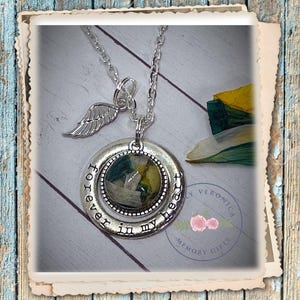 May include: Silver necklace with a round pendant that says "forever in my heart". The pendant has a clear glass insert with pressed flowers inside. The necklace also has a small angel wing charm.