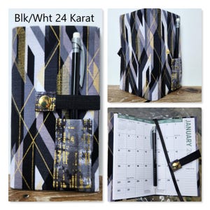 Op de afbeelding: Een stoffen plannerhoes met een geometrisch patroon in zwart, wit en goud, gelabeld Blk/Wht 24 Karat. De hoes bevat een elastische band met een goudkleurige drukknoop, een penlus en een buitenvak met daarin een zwarte pen.