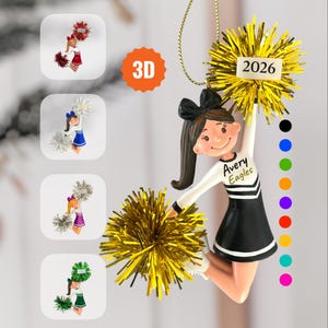 May include: A 3D cheerleader ornament featuring a figure in a black and white uniform with the text Avery Eagles, holding gold pom-poms and a 2026 tag. Four smaller circular inset images show variations in red, blue, purple, and green.
