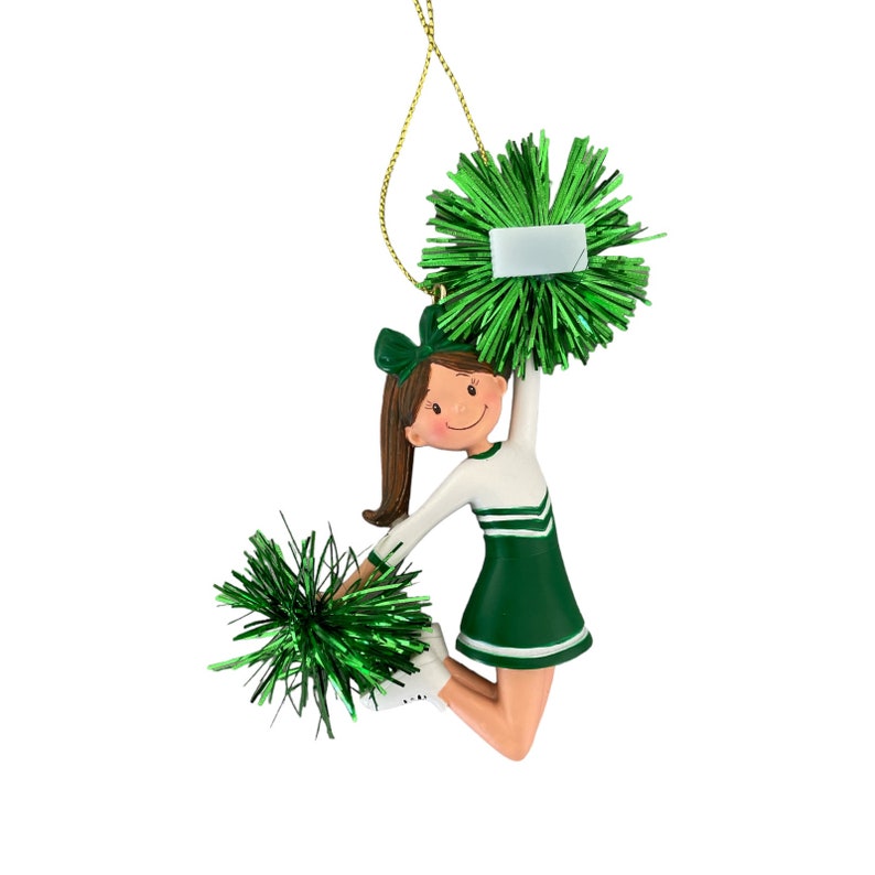 May include: Green and white cheerleader ornament with pom-poms. The ornament is a girl with brown hair and a white and green uniform.