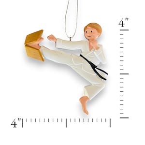 May include: A white karate ornament with a black belt breaking a wooden board. The ornament is 4 inches tall.