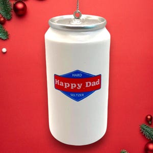 May include: White aluminum can Christmas ornament with a blue and red label that reads "Hard Happy Dad Seltzer".