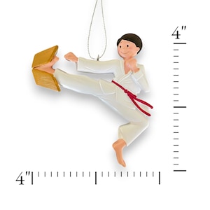 May include: A white karate ornament with a red belt breaking a wooden board. The ornament is 4 inches tall.