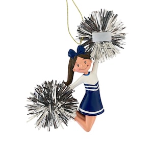 May include: A blue and white cheerleader ornament with silver pom-poms. The ornament is holding up the pom-poms and has a smiling face.