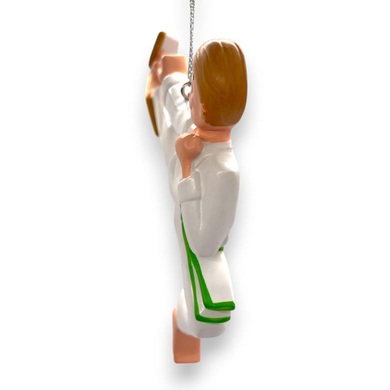 May include: A white and green karate ornament with a person in a white karate uniform kicking in the air.