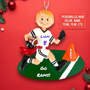 May include: A personalized Christmas ornament featuring a boy in a white and black football uniform running with a football. The ornament is on a green field with a white line and a cone with the number 2024. The ornament also includes the text "Liam 8" and "Go Rams!"