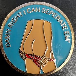 May include: A round, gold-rimmed coin with a blue center featuring a cartoon illustration of a person's lower body. The person is pulling down their red underwear. The text "DAMN RIGHT I CAN SEPERATE EM" is in gold lettering around the edge.