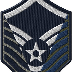 May include: A blue, white, and green military rank patch with a star and wings. The patch has a chevron design with three stripes.