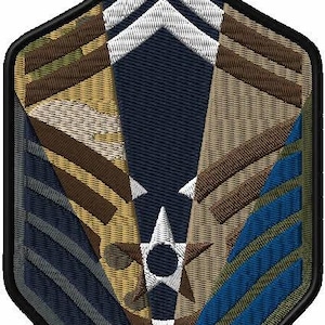 May include: A blue, brown, and white embroidered patch with a star and chevron design. The patch is shaped like a shield and has a black border.
