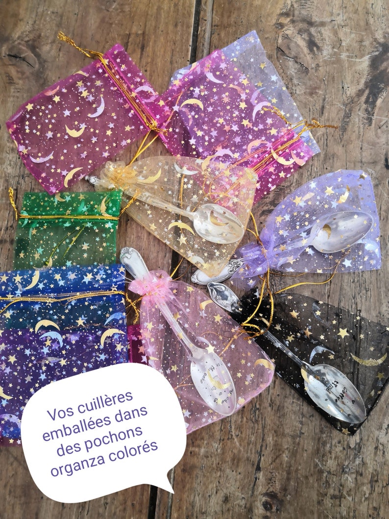 Pu&ograve; includere: Assortimento di cucchiai decorativi in sacchetti di organza colorati. I sacchetti sono adornati con stelle dorate e lune crescenti. I cucchiai presentano disegni decorativi e testo. I sacchetti sono in vari colori, tra cui rosa, verde e viola.