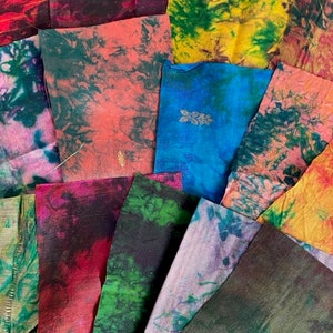 May include: A collection of colourful fabric scraps with tie-dye patterns in shades of green, blue, red, orange, yellow, and purple. The fabric scraps are arranged in a random pattern.