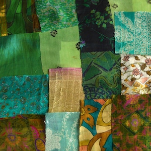 May include: A patchwork of green fabrics, including silk and patterned textiles. The arrangement features squares and rectangles in shades from light to dark green, with floral and abstract designs. Some pieces have gold accents.
