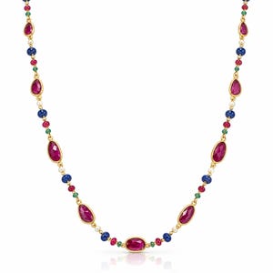 Op de afbeelding: Een gouden ketting met een herhalend patroon van gefacetteerde ovaalvormige roze edelstenen, kleine ronde blauwe lapis lazuli kralen, piepkleine groene smaragdkleurige steentjes en kleine witte parels die symmetrisch langs de schakels zijn gerangschikt.