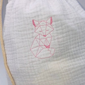 May include: White drawstring bag with a pink geometric fox design embroidered on the front.