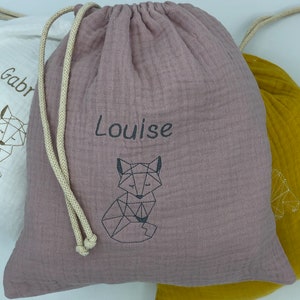 May include: A dusty rose drawstring bag with a geometric fox design and the name "Louise" embroidered on the front.