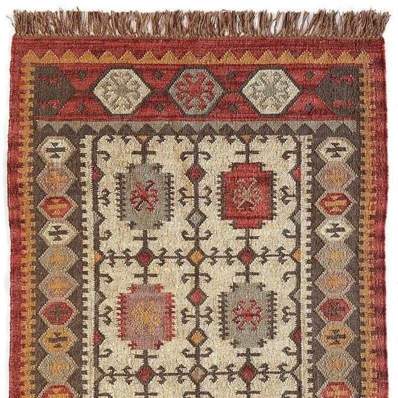 May include: A rectangular rug with a cream central field and geometric patterns in red, brown, and grey. The border is a mix of red, brown, and gold, with a fringed edge. The rug's design is intricate and detailed.