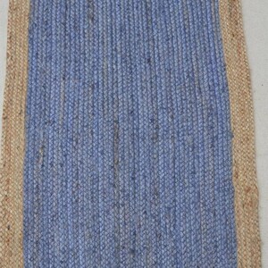 May include: A blue jute rug with a natural jute border. The rug has a woven texture and is rectangular in shape.