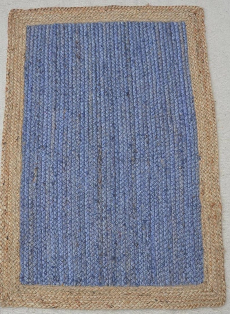 May include: A blue jute rug with a natural jute border. The rug has a woven texture and is rectangular in shape.