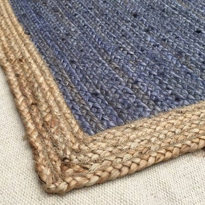 May include: A blue and natural jute rug with a woven design. The rug has a thick, natural jute border.
