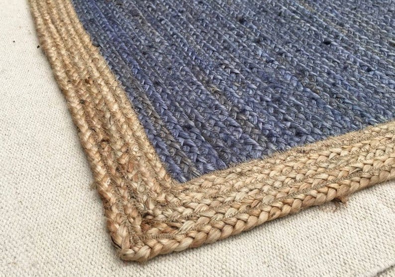 May include: A blue and natural jute rug with a woven design. The rug has a thick, natural jute border.