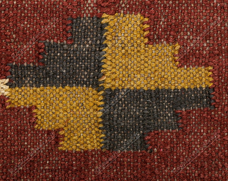 May include: Close-up of a woven fabric with a geometric pattern in shades of red, black, and gold.