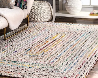 May include: A white, hand-woven rug with a diamond pattern. The rug is made of colorful, recycled materials and has a natural, rustic look.