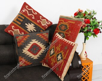 May include: Four decorative throw pillows with geometric patterns in shades of red, black, brown, and beige. The pillows are made of a woven fabric and have a rustic, hand-crafted look.