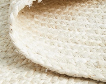 May include: Close-up of a white woven rug with a textured surface. The rug is made of natural fibers and has a simple, elegant design.