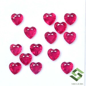 May include: A collection of 14 heart-shaped ruby gemstones. The rubies are a deep red color and have a polished finish.