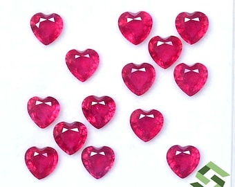 May include: A collection of 14 heart-shaped ruby gemstones. The rubies are a deep red colour and have a polished finish.