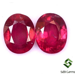 May include: Two oval-shaped, red gemstones. The gemstones are faceted and have a polished finish.