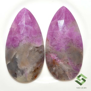 Può includere: Due cabochon di pietra preziosa a forma di pera, di colore rosa e grigio. Le pietre hanno un aspetto screziato con sfumature di rosa, grigio e marrone.