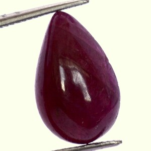 May include: A deep red pear-shaped gemstone with a smooth, polished surface.