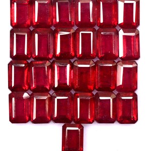 May include: Twenty-five red ruby gemstones in a rectangular emerald cut, arranged in four rows with one gemstone at the bottom.
