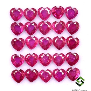 May include: Twenty-five heart-shaped ruby gemstones arranged in five rows of five. The rubies are a deep pink color and have a faceted cut.